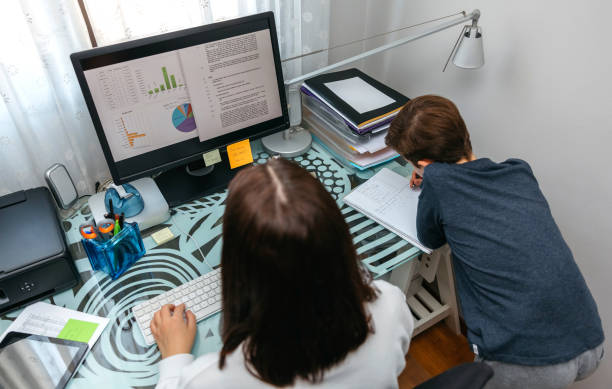 istock Woman teleworking at home while her son studies 1302437887