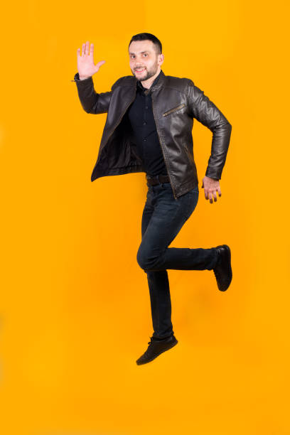 istock Cheerful positive man jumped on orange background 1302438756