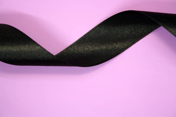 istock Black ribbon on a purple background. Needlework. 1302439676