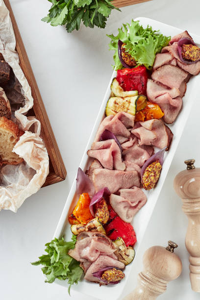 Sliced Beef or Pork with Marinated Vegetables and Sauce. Beautifully decorated catering banquet menu. Food snacks and appetizers for buffet on white background