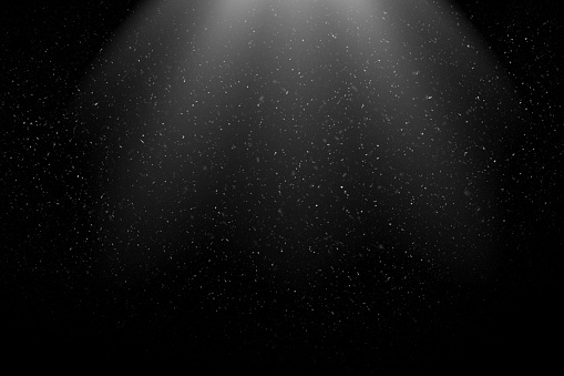 Dust Particles / Snowfall in the Light Beam against Black Background