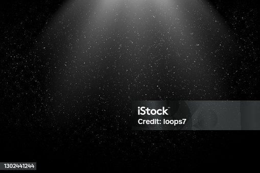 istock Dust Particles / Snowfall in the Light Beam against Black Background 1302441244