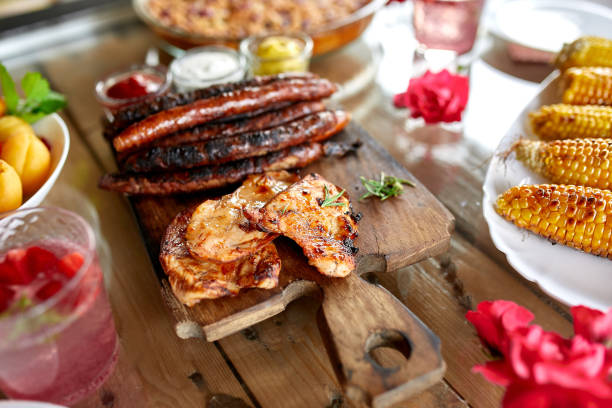istock Dinner table with meat grill, roast vegetables, sauces and lemonade, appetizers variety serving on party outdoor table. 1302441305