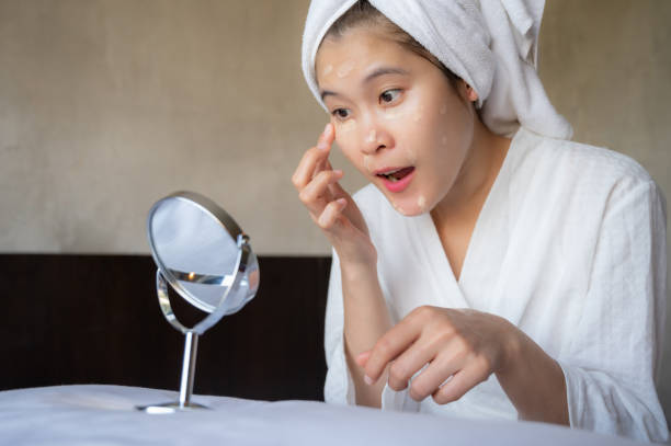 femme asiatique essayant de marquer et appliquant le correcteur de crème sur son visage. - make up foundation cosmetics face powder photos et images de collection
