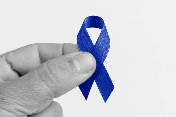 mano sosteniendo un noviembre azul. cinta azul sobre fondo blanco, cáncer colorrectal, conciencia de cáncer de próstata, conciencia de la salud de los hombres. - hypo fotografías e imágenes de stock