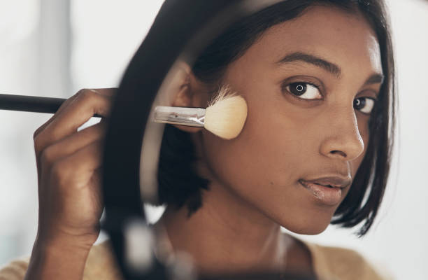 Beauty is in the eye of the makeup brush holder Shot of a young woman applying makeup while filming a beauty tutorial at home concealer stock pictures, royalty-free photos & images