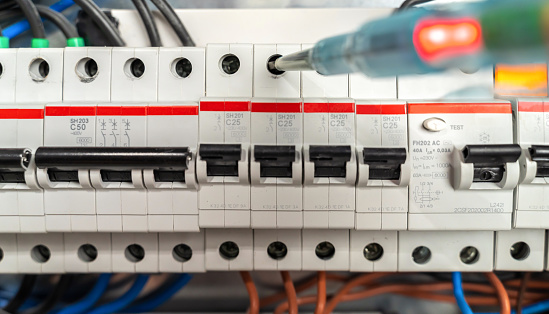 Technician checking fuse box, close-up. Male electrician working with phase meter. Photo is taken in studio environment with Sony A7III camera.