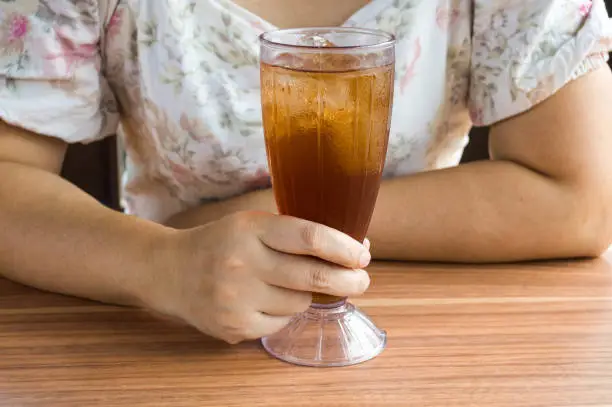 Photo of Unrecognized Young Woman Holding Glass of iced Tea in One Hand