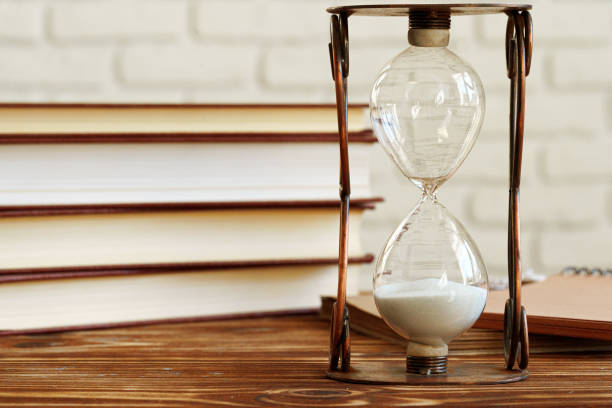 istock Vintage hourglass against a stack of old books 1302446446