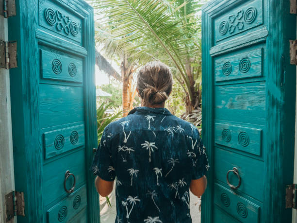 uomo che apre le porte della villa sulla spiaggia di lusso - luxury hotel palm tree lush foliage asia foto e immagini stock