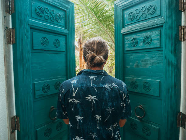 uomo che apre le porte della villa sulla spiaggia di lusso - luxury hotel palm tree lush foliage asia foto e immagini stock