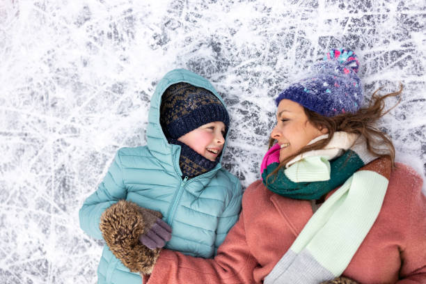 istock Mother and son lying down on frozen lake surface and smiling 1302447484