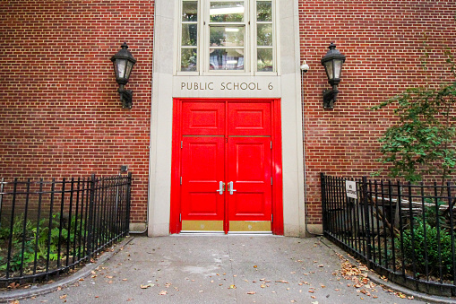 New York, USA - August 7, 2018: the red door of a public school closed during the summer