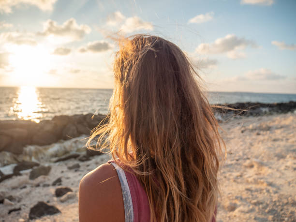 istock Woman contemplates sunrise from beach 1302448599