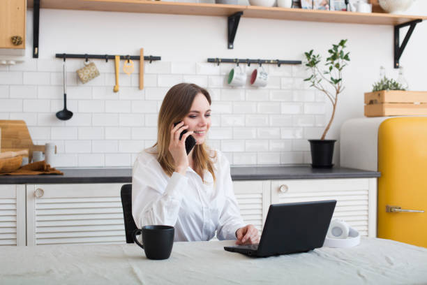 istock attractive young woman working with laptop in the kitchen, drinking coffee 1302448923