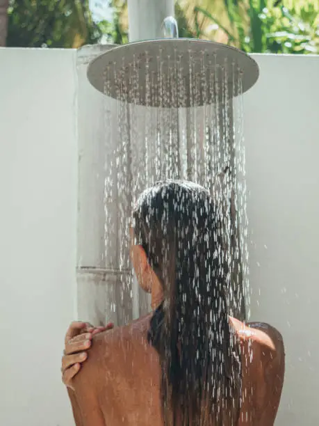 Photo of Woman takes outdoor shower in tropical garden