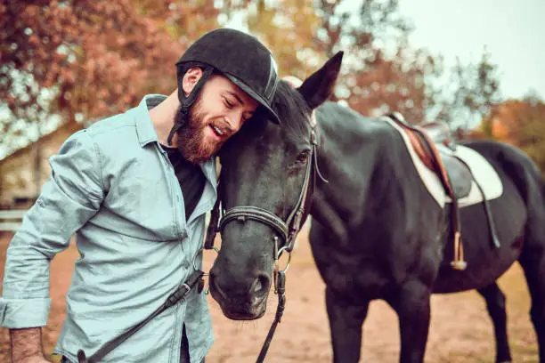 Modern Male Jockey Embracing Horse After Fun Day Riding On Ranch