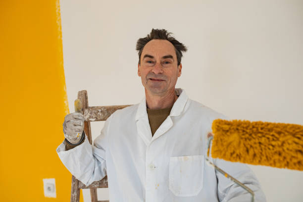 istock Active senior manual worker is pleased with yellow color with which he has painted the wall 1302451006