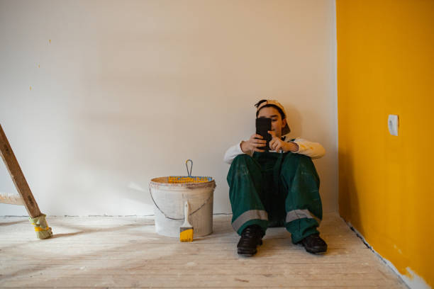 istock Young boy taking a break from painting and spending time on his smart phone 1302451071