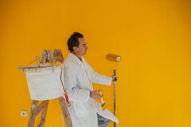 istock Manual worker looking at the fresh painted yellow wall and admires to his work 1302451125