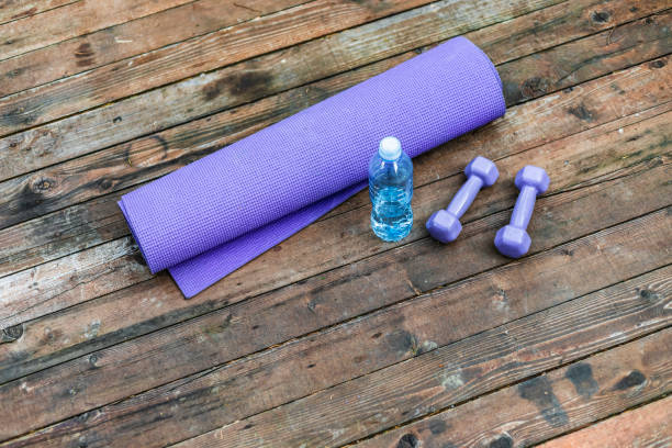 Dumbbells and yoga mat on wood table