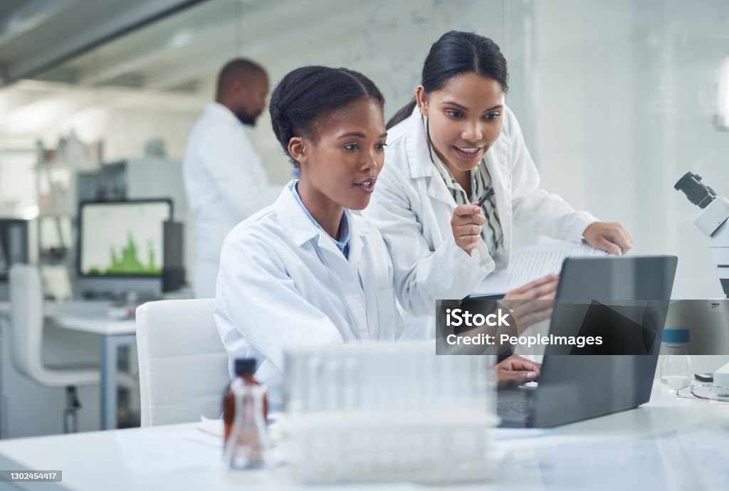 Improving lives one collaboration at a time Shot of two young scientists using a laptop in a laboratory Laboratory Stock Photo