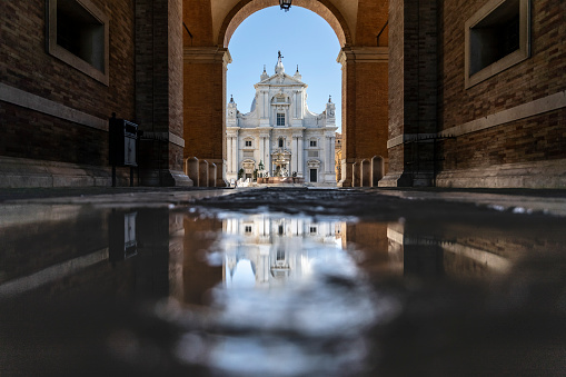 Piazza della Madonna, Basilica of the Holy House reflected in the water, Loreto town, Italy.