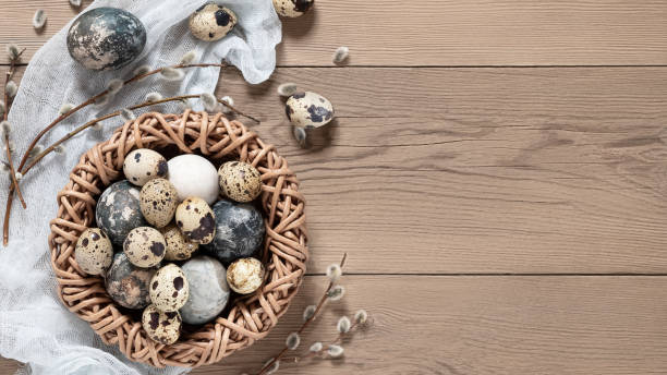 istock Easter composition - Easter eggs painted with natural dyes in a wicker nest on a wooden table, copyspace 1302457684