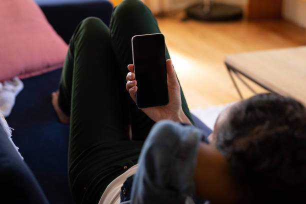 istock Caucasian woman using smartphone lying on sofa at home 1302461442