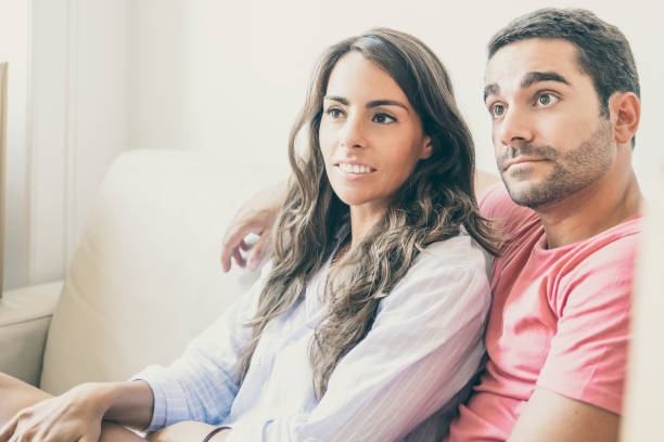 istock Positive focused Latin couple sitting on couch 1302461501