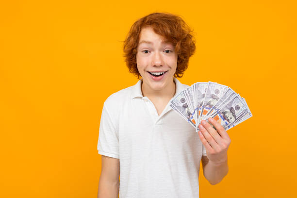 istock guy in a white shirt holds money won on a yellow background with copy space 1302462450