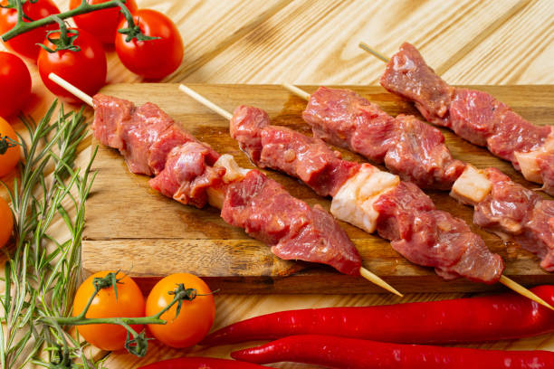 istock Raw kebab from meat on a wooden background with vegetables. 1302464278