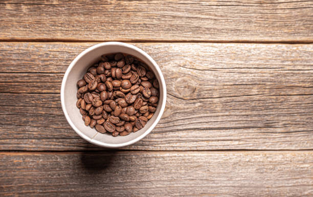 istock Paper cup with coffee beans on wooden table. 1302464353