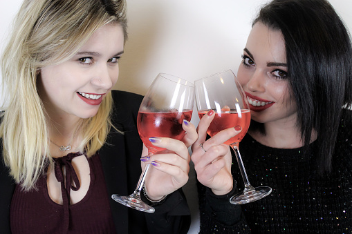 Two young women celebrate an event with a glass of drink