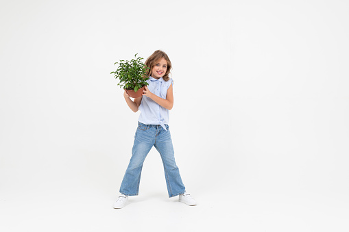teenager girl holding a houseplant with green leaves on a white background with copy space.
