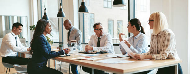 istock Diverse group of businesspeople talking together around an office table 1302466517