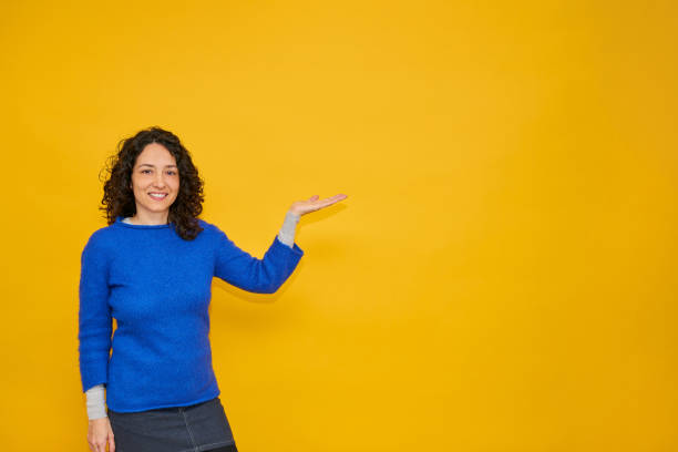 istock Pretty young woman smiles pointing to her side 1302466731