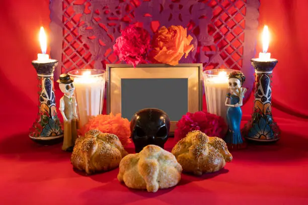 Photo of Day of the Dead offering from central Mexico with papel picado, veladoras, photography, flowers and bread of the dead