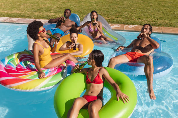 istock Diverse group of friends having fun playing on inflatables in swimming pool 1302470089