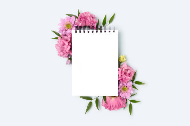 istock Floral frame made of eustoma flower and empty notepad mockup on a blue pastel background. 1302470165