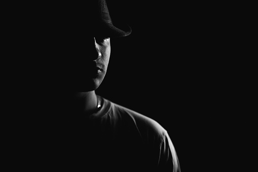 Low key portrait of a young man, almost in silhouette. Studio shot against black background.