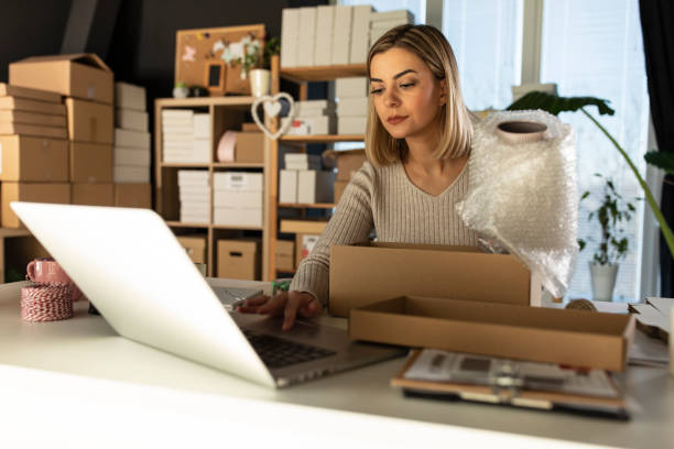 istock Wrapping customer's order in bubble pack and checking details on laptop 1302473298