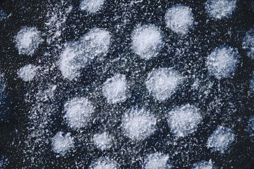 Dark abstract background of frozen snow and ice on concrete