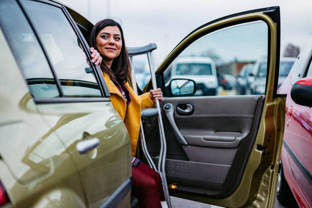 mujer con elenco saliendo del coche - crutch fotografías e imágenes de stock