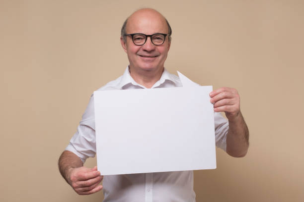 istock Senior hispanic man in glasses holding a blank placard 1302475969