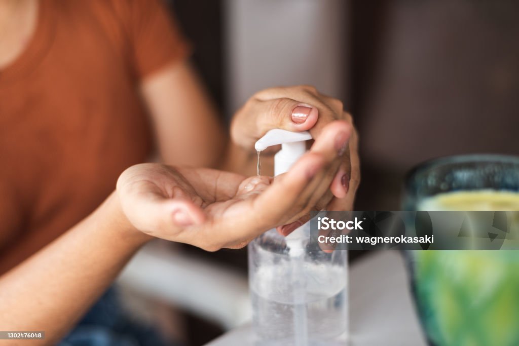 Young woman sanitizing her hands before snack at a restaurant Hand Sanitizer Stock Photo