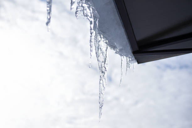 istock A long icicle melts at the edge of a rooftop outside 1302476555