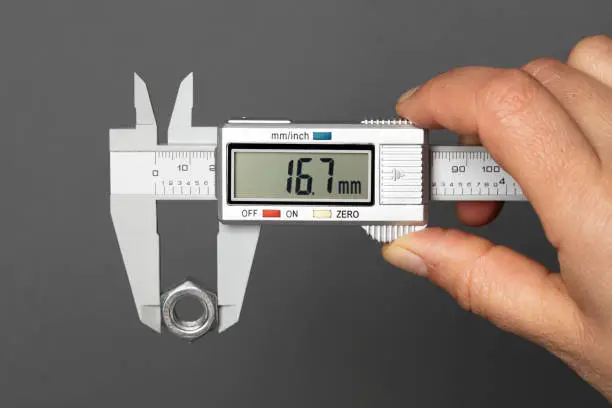 Digital  caliper measuring metal nut, isolated on grey background