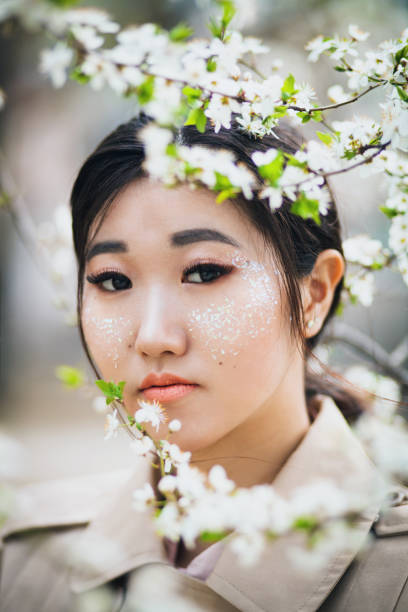 istock Beautiful woman with shiny makeup surrounded by cherry blossom 1302481921