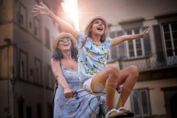 una madre montando una bicicleta y su hija está sentada en el manillar. - italy summer florence italy tuscany fotografías e imágenes de stock